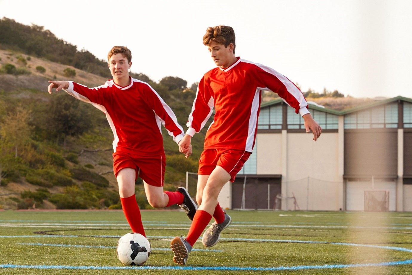 dwaj chłopcy trenują piłkę nożną na boisku szkolnym